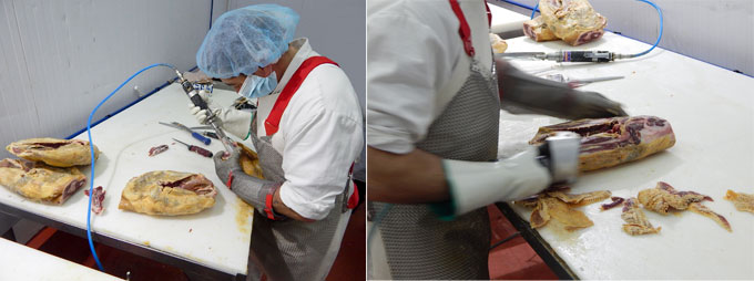 Dos empleados realizando el deshuesado y descortezado de las piezas de jamn antes de pasar a la sala de prensado