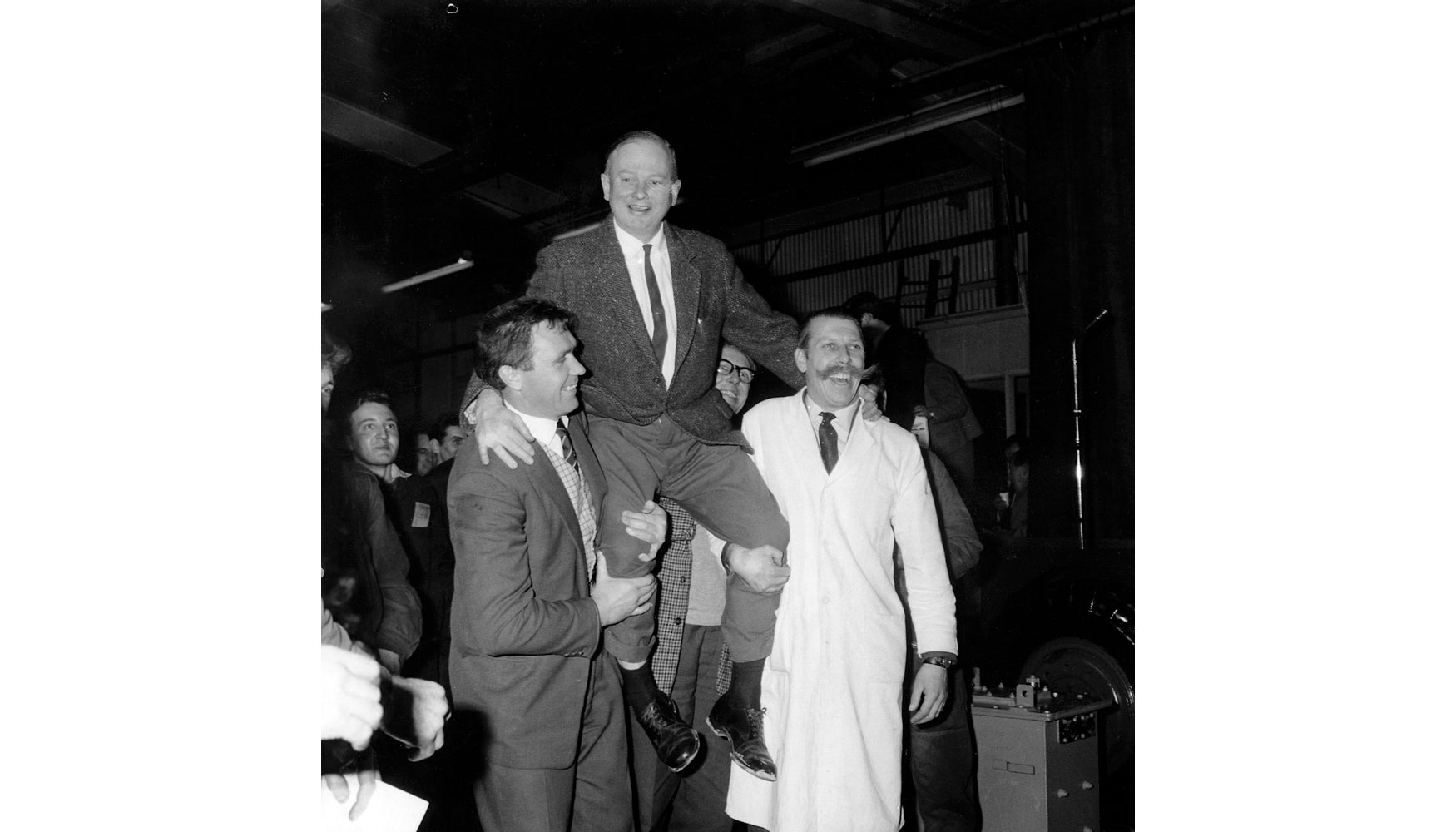 1964. Mr Bamford es subido a hombros por sus empleados Bill Hirts y John Wheeldon tras aununciar el reparto de una bonificacin de 250...