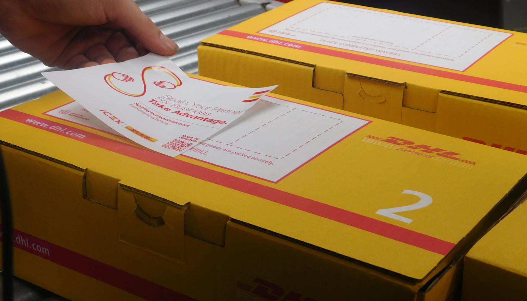 Un trabajador de DHL coloca la pegatina 'Spain Your Partner' sobre un paquete en las instalaciones de DHL en Madrid...