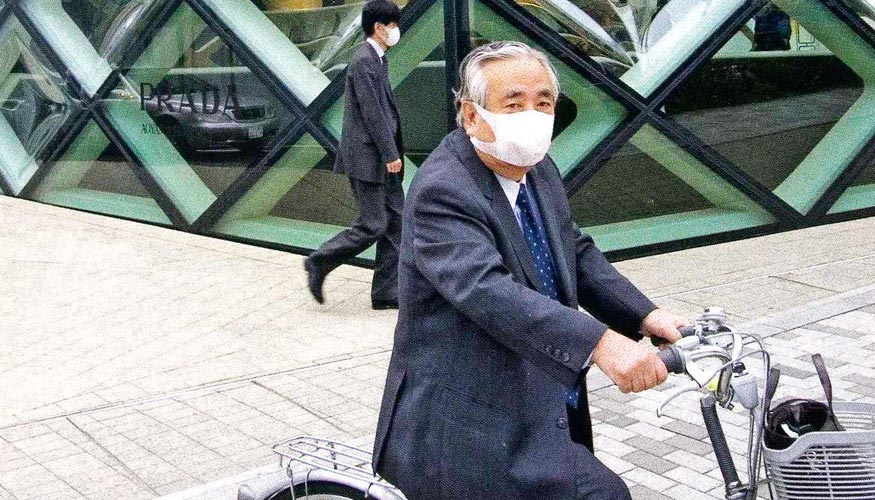En bicicleta un japons filtra con su careta el aire ambiente
