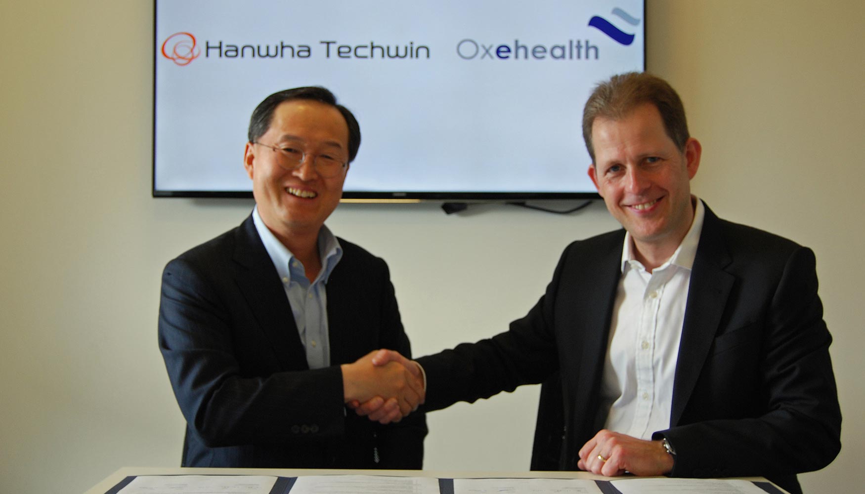 Cheol Kyo Kim, presidente y CEO de Hanwha Techwin Co. Limited (derecha) y Jonathan Chevallier, CEO de Oxehealth