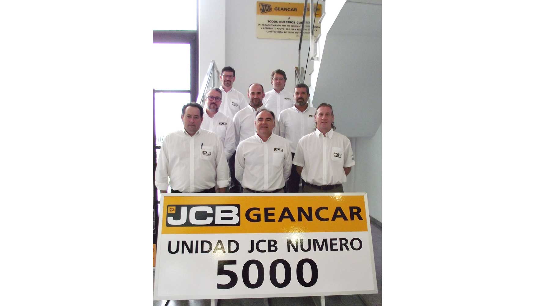 El equipo de Geancar posa orgulloso con el cartel de las 5.000 unidades JCB