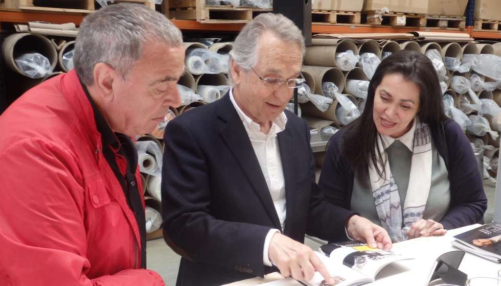 Albert Carol, mostrando el libro que recoge su trayectoria profesional a dos de los invitados al acto