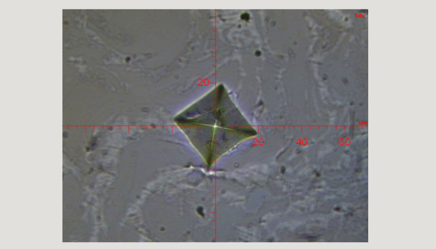 Figura 3. Imagen tomada a travs de microscopio de una huella de penetracin con punta Vickers. Escala en micras
