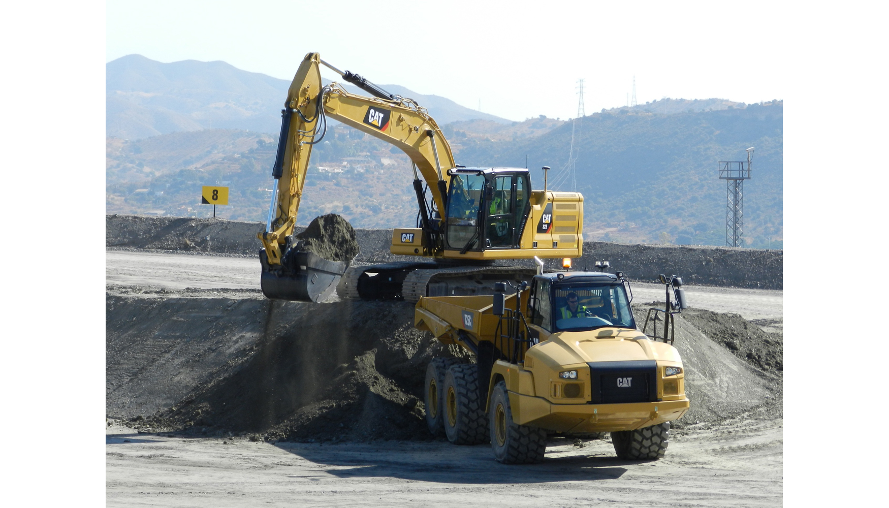 Nueva excavadora 323 de Caterpillar cargando en dumper articulado