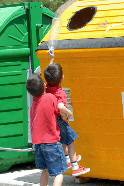 Nios depositando un envase de plstico en el contenedor amarillo