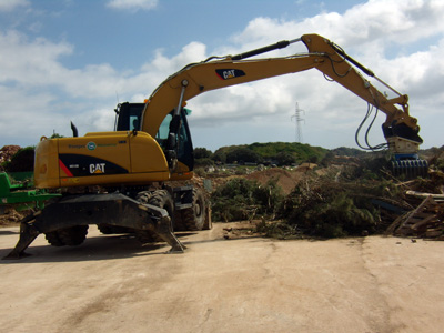 La excavadora de ruedas M313D, equipada con pinzas de reciclaje, se encarga de seleccionar ramas de poda y extraer otros materiales para su reciclaje...