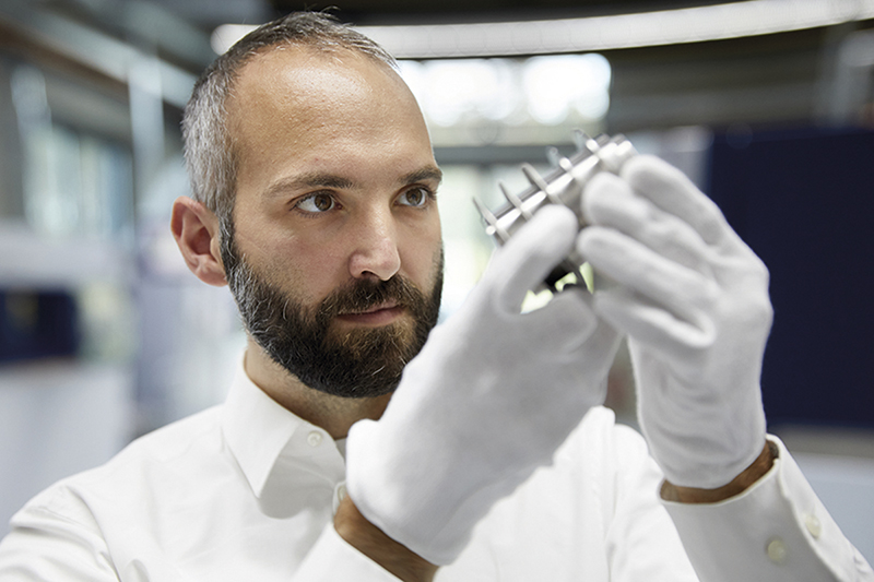 Thomas Schopphoven, chefe do grupo de Depsito de Material Laser, no Fraunhofer ILT, inspeciona um componente de metal...