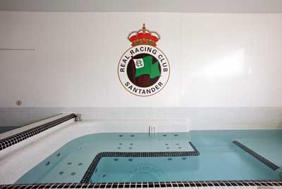 Detalle del escudo realizado con Altro Whiterock, que reviste las paredes de las duchas, la baera de hidromasaje y la piscina de agua fra...