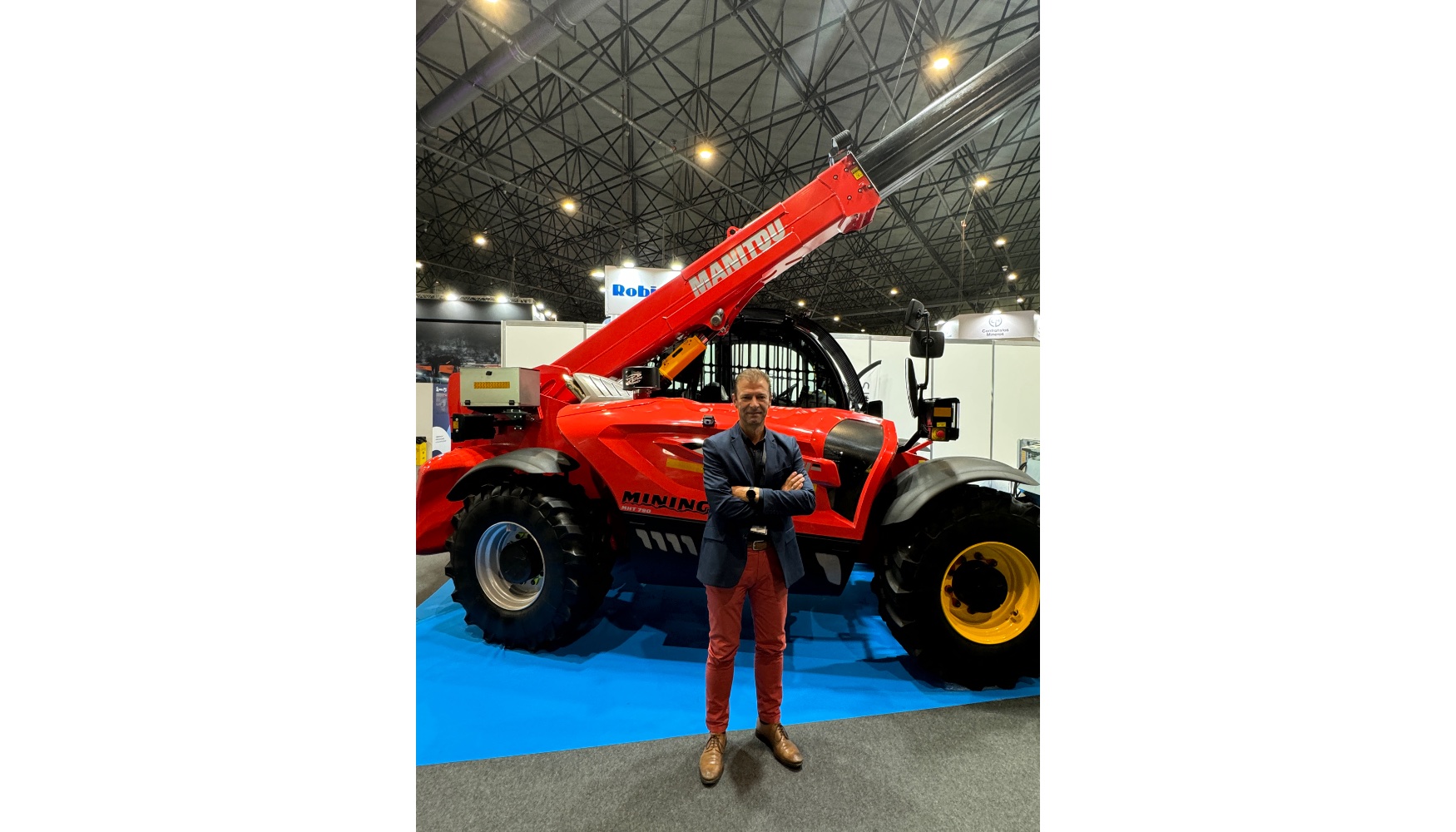 Rafael Pars Prieto, administrador y director comercial de Cema Maquinaria, junto al manipulador Manitou MHT 790 Mining expuesto en el MMH...