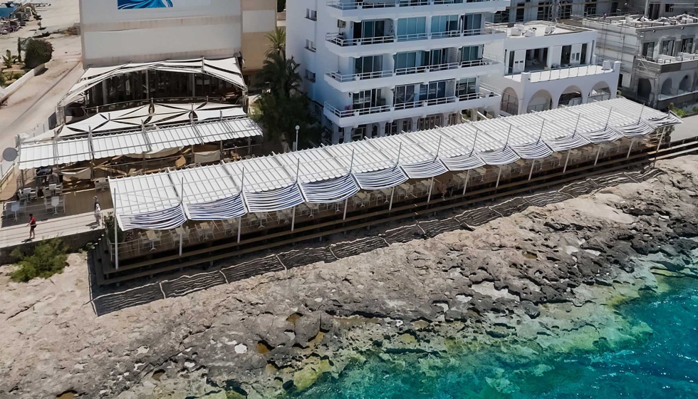 Os 17 toldos Aneas 80x40 Saxun instalados continuamente no terrao do Caf del Mar traam uma linha reta paralela ao Mar Mediterrneo...