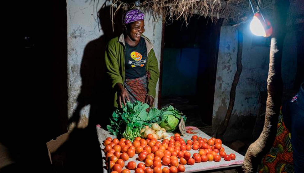Una comerciante utiliza su luz para vender sus productos en el mercado local. Foto: SolarAid, Jason J. Mulikita