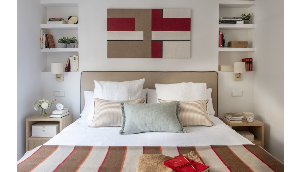 Dormitorio principal flanqueado por armarios a medida con frentes lacados y molduras rectangulares que enmarcan papel pintado texturizado...