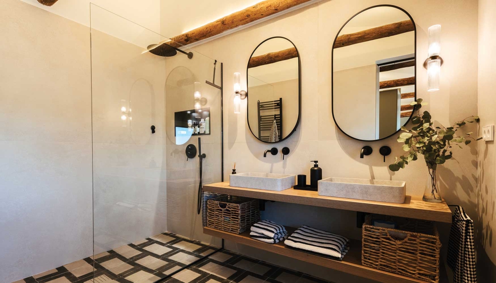 El bao combina un marcado contraste en blanco y negro con detalles en madera, como el mueble bajo lavabo y las vigas vistas...