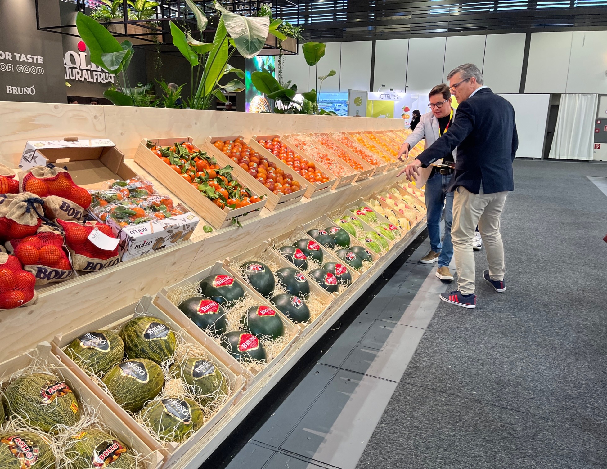 Dos profesionales observan las frutas y verduras de una de las empresas expositoras en Fruit Logistica 2025
