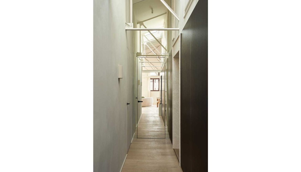 El acceso a la vivienda se organiza mediante un pasillo definido por una pared estucada con acabado de trazo vertical y un sistema de panelado en...