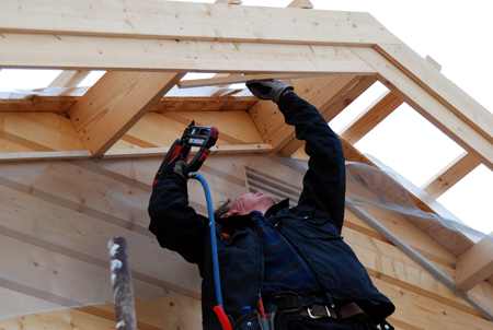Un operario monta una cubierta para una casa de madera