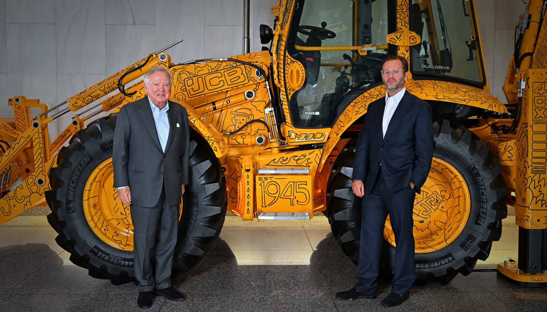 Lord Bamford y George Bamford junto al modelo especial que conmemora la retroexcavadora un mill�n producida por JCB...
