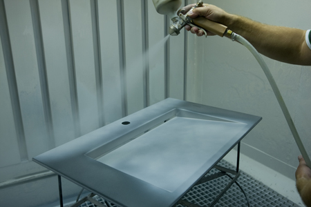 Los lavabos conformados en acero se pulverizan manualmente con un finsimo vidriado de base