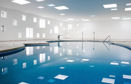 Las perforaciones cuadradas que se han incluido en la estructura permiten que la luz inunde el interior de la piscina