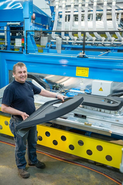 A worker shows the result of the transformation of the laminate with the Kiefel machine technology