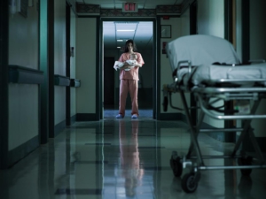 Nurse holding newborn baby in hospital corridor